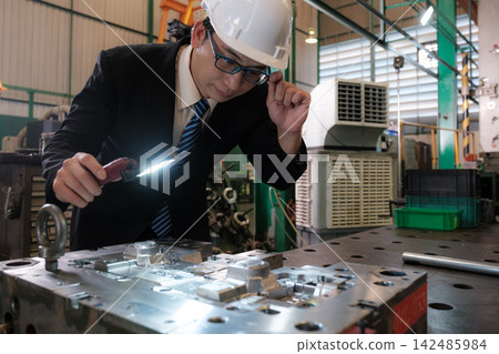 The engineer checks the parts coming out of the machine. The engineer checks the parts coming out of the machine. 142485984