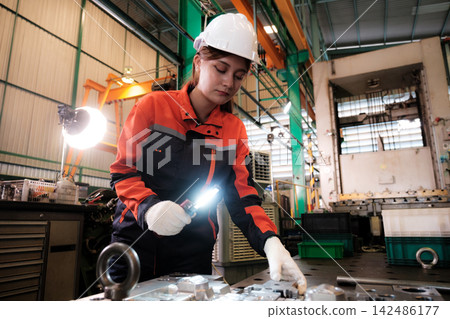 The engineer checks the parts coming out of the machine. The engineer checks the parts coming out of the machine. 142486177