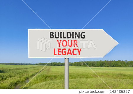 Building your legacy words symbol. Concept words Building your legacy on beautiful grey road sign. Beautiful blue sky green grass background. Business building your legacy concept. Copy space. Building your legacy words symbol. Concept words Building your legacy on beautiful grey road sign. Beautiful blue sky green grass background. Business building your legacy concept. Copy space. 142486257