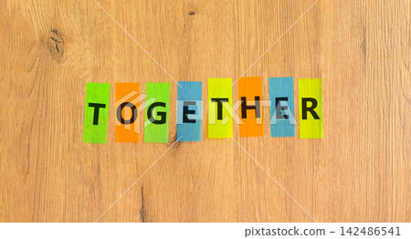 Together word symbol. Concept word Together on beautiful colored papers. Beautiful wooden background. Business support help together word concept. Copy space. Together word symbol. Concept word Together on beautiful colored papers. Beautiful wooden background. Business support help together word concept. Copy space. 142486541