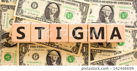Stigma word symbol. Concept word Stigma on beautiful wooden blocks. Beautiful dollar bills background. Beautiful dollar bills. Business psychological stigma word concept. Copy space. Stigma word symbol. Concept word Stigma on beautiful wooden blocks. Beautiful dollar bills background. Beautiful dollar bills. Business psychological stigma word concept. Copy space. 142486699