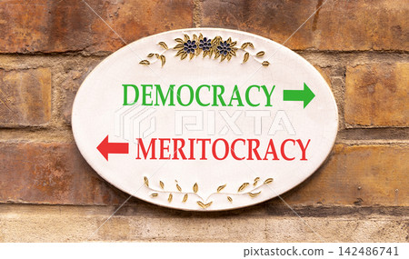 Democracy or meritocracy words symbol. Concept words Democracy Meritocracy on beautiful white sign plate. Beautiful brick wall background. Business democracy meritocracy concept. Copy space Democracy or meritocracy words symbol. Concept words Democracy Meritocracy on beautiful white sign plate. Beautiful brick wall background. Business democracy meritocracy concept. Copy space 142486741