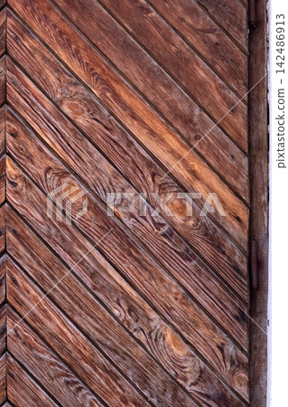 Wooden planks arranged diagonally, forming a textured surface with visible grain and knots, showcasing natural timber for a rustic or vintage aesthetic Wooden planks arranged diagonally, forming a textured surface with visible grain and knots, showcasing natural timber for a rustic or vintage aesthetic 142486913