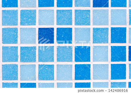 Mosaic blue tiles displaying varying shades of color and grainy texture, creating a geometric grid pattern with white grout lines, useful as a decorative surface or background Mosaic blue tiles displaying varying shades of color and grainy texture, creating a geometric grid pattern with white grout lines, useful as a decorative surface or background 142486916