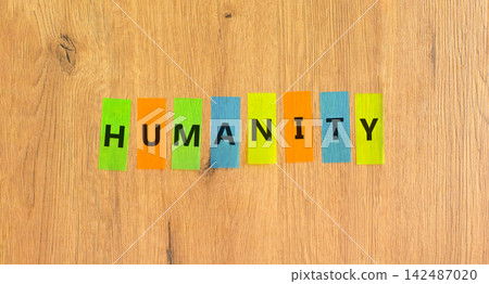 Humanity word symbol. Concept word Humanity on beautiful colored papers. Beautiful wooden background. Business support help humanity word concept. Copy space. Humanity word symbol. Concept word Humanity on beautiful colored papers. Beautiful wooden background. Business support help humanity word concept. Copy space. 142487020