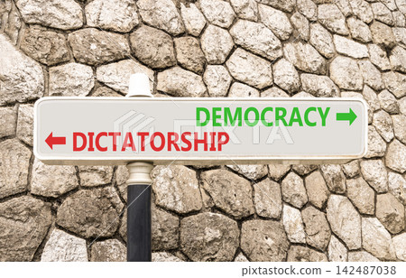 Democracy or dictatorship words symbol. Concept words Democracy Dictatorship on beautiful white road sign. Beautiful stone wall background. Business democracy dictatorship concept. Copy space Democracy or dictatorship words symbol. Concept words Democracy Dictatorship on beautiful white road sign. Beautiful stone wall background. Business democracy dictatorship concept. Copy space 142487038