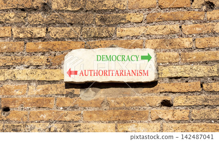 Democracy or authoritarianism symbol. Concept words Democracy Authoritarianism on beautiful white sign plate. Beautiful brick wall background. Business democracy authoritarianism concept. Copy space Democracy or authoritarianism symbol. Concept words Democracy Authoritarianism on beautiful white sign plate. Beautiful brick wall background. Business democracy authoritarianism concept. Copy space 142487041