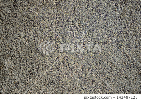 Grey concrete wall texture with rough granular surface and natural sunlight creating subtle shadows, forming an abstract background for design and decor Grey concrete wall texture with rough granular surface and natural sunlight creating subtle shadows, forming an abstract background for design and decor 142487123