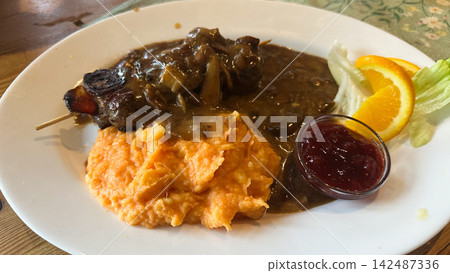 Venison with mushroom gravy, sweet potato mash, Lactuca sativa and Citrus sinensis. The scene represents comfort, harvest and tradition. Venison with mushroom gravy, sweet potato mash, Lactuca sativa and Citrus sinensis. The scene represents comfort, harvest and tradition. 142487336