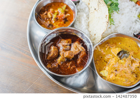 Indian curry and basmati rice served on a stainless steel plate: South Indian thali (meals). Indian curry and basmati rice served on a stainless steel plate: South Indian thali (meals). 142487350