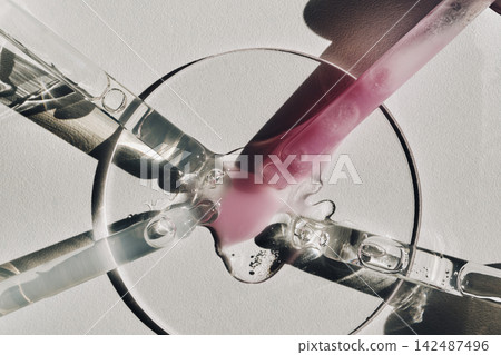Serum droplets merging on petri dish with pipettes creating blend Serum droplets merging on petri dish with pipettes creating blend 142487496