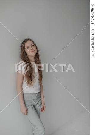 Dreamy preteen girl with long hair leaning against empty white wall copyspace Dreamy preteen girl with long hair leaning against empty white wall copyspace 142487908