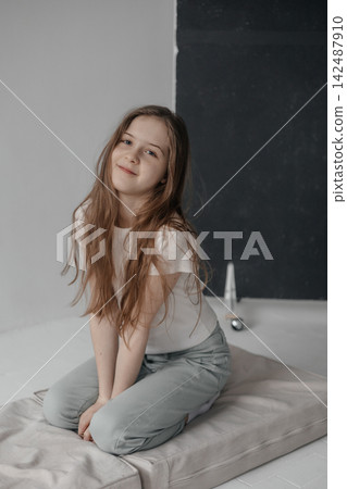 Dreamy preteen girl with long hair leaning against empty white wall copyspace Dreamy preteen girl with long hair leaning against empty white wall copyspace 142487910