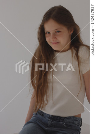 Pretty preteen girl with long brown hair smiling on clean white background 142487937