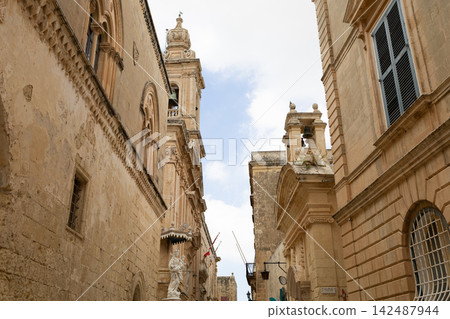 View of a historic medieval stone street framed by an ancient archway in Malta. View of a historic medieval stone street framed by an ancient archway in Malta. 142487944