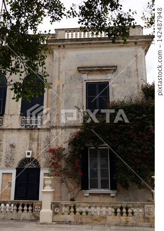 Historic stone palace facade with traditional blue shutters and blooming bougainvillea. Historic stone palace facade with traditional blue shutters and blooming bougainvillea. 142487948