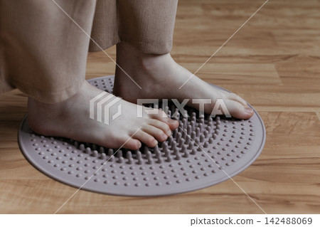 Sole stimulation. girl stands on massage mat. Massage and healthy lifestyle. Treatment of flat feet and hallux valgus. Sole stimulation. girl stands on massage mat. Massage and healthy lifestyle. Treatment of flat feet and hallux valgus. 142488069