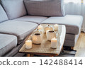 Autumn fall mood composition for hygge home decor. Hot tea or coffee drink in pumpkin's shaped cups, pumpkin decor and burning candles on the coffee table. Festive autumn, fall mood home decor 142488414