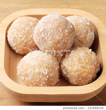 Homemade Brazilian coconut beijinho in a wooden bowl traditional sweets served at parties and celebrations. Homemade Brazilian coconut beijinho in a wooden bowl traditional sweets served at parties and celebrations. 142488430