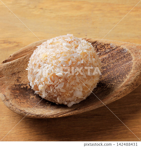 Homemade Brazilian coconut beijinho on a wooden spoon traditional sweets served at parties and celebrations. 142488431