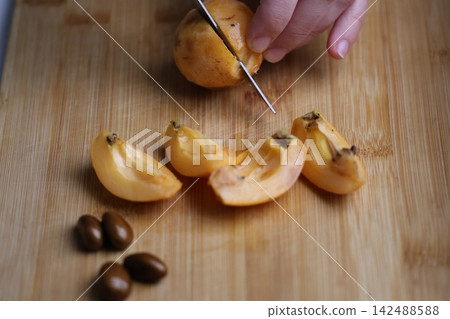 Slicing fresh fruit. Hand holding loquats. Yellow fruit hand. medlar in hand, close-up. High quality photo Slicing fresh fruit. Hand holding loquats. Yellow fruit hand. medlar in hand, close-up. High quality photo 142488588