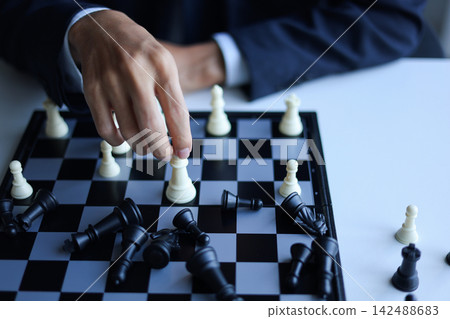 Businessman playing chess game; business strategy, leadership and management concept. Businessman playing chess game; business strategy, leadership and management concept. 142488683