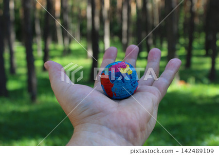 Small Globe On A Human Palm At The Forest With Green Trees Small Globe On A Human Palm At The Forest With Green Trees 142489109