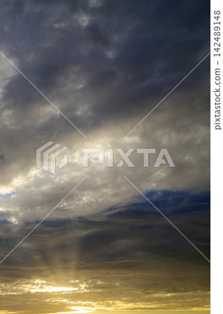 stormy gray clouds with breaking golden sunbeams near horizon at sunset stormy gray clouds with breaking golden sunbeams near horizon at sunset 142489148