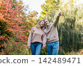 Young happy Caucasian couple in love holding hands and enjoying the moment during romantic walk on nature in the fall park. Autumn mood. Youth feelings and first love emotions concept. 142489471