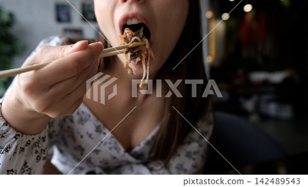 Close-up of Caucasian woman eating pan-Asian cuisine Close-up of Caucasian woman eating pan-Asian cuisine 142489543