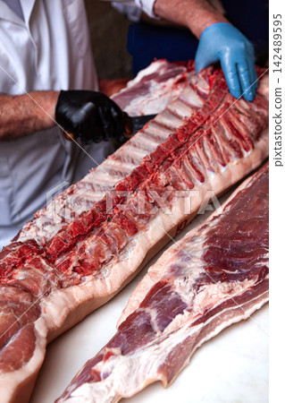 Butchering a side of pork in a butcher shop Butchering a side of pork in a butcher shop 142489595