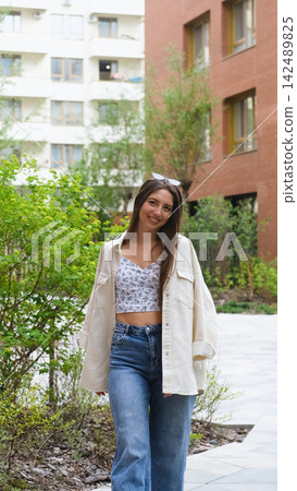 An attractive woman with a beautiful smile and long hair is spinning, walking around the city, posing for the camera. An attractive woman with a beautiful smile and long hair is spinning, walking around the city, posing for the camera. 142489825