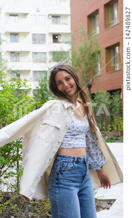 An attractive woman with a beautiful smile and long hair is spinning, walking around the city, posing for the camera. An attractive woman with a beautiful smile and long hair is spinning, walking around the city, posing for the camera. 142489827