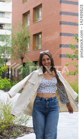 An attractive woman with a beautiful smile and long hair is spinning, walking around the city, posing for the camera. An attractive woman with a beautiful smile and long hair is spinning, walking around the city, posing for the camera. 142489828