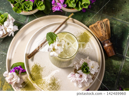 Iced matcha latte standing on ceramic plate with flowers and chasen Iced matcha latte standing on ceramic plate with flowers and chasen 142489960