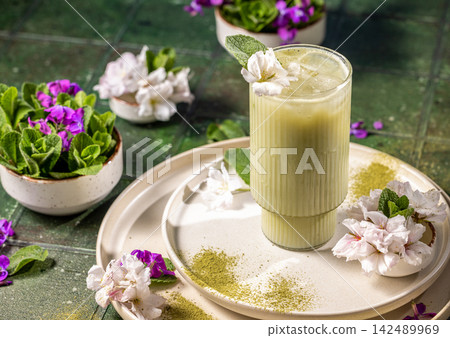 Iced matcha latte standing on table decorated with flowers 142489969