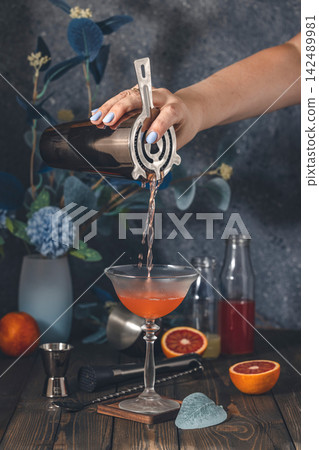 Bartender pouring blood orange craft cocktail into glass Bartender pouring blood orange craft cocktail into glass 142489981