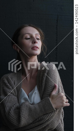 Portrait of a beautiful young girl on a dark studio background. Beautiful natural woman posing for the camera Portrait of a beautiful young girl on a dark studio background. Beautiful natural woman posing for the camera 142490023