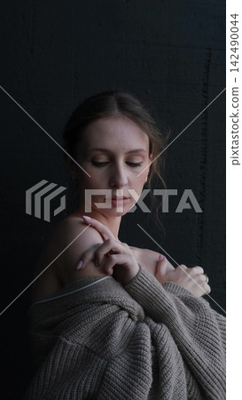Portrait of a beautiful young girl with bare shoulders on a dark studio background. Beautiful natural woman posing for the camera Portrait of a beautiful young girl with bare shoulders on a dark studio background. Beautiful natural woman posing for the camera 142490044