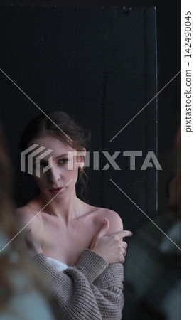 Portrait of a beautiful young girl with bare shoulders on a dark studio background. Beautiful natural woman posing for the camera Portrait of a beautiful young girl with bare shoulders on a dark studio background. Beautiful natural woman posing for the camera 142490045