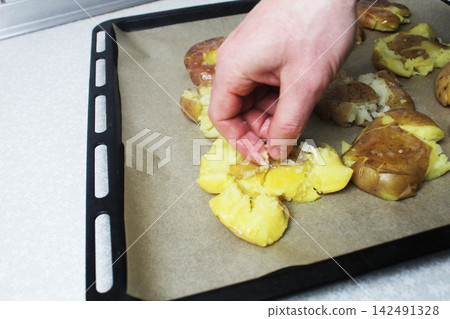 Cooking crispy roasted smashed baked potatoes. Sprinkles potatoes with cheese, salt, pepper. 142491328