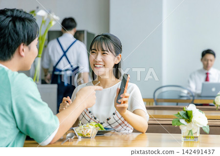 A young couple looking at a smartphone at a cafe A young couple looking at a smartphone at a cafe 142491437