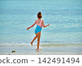 Child girl in blue swimsuit running towards calm turquoise water at Pattaya Beach, Koh Lipe, Thailand 142491494