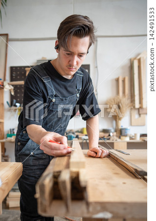 Qualified master restorer preparing patch for old window frame at workbench in restoration studio. Qualified master restorer preparing patch for old window frame at workbench in restoration studio. 142491533