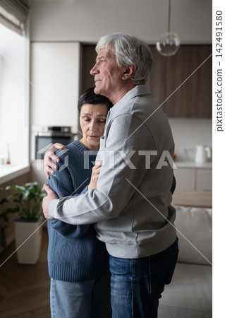 Tired mature wife with closed eyes being tightly embraced by husband, seeking emotional support Tired mature wife with closed eyes being tightly embraced by husband, seeking emotional support 142491580