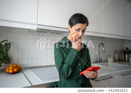 Pensive sad senior woman reading upsetting web feed media content on phone, distress shock news Pensive sad senior woman reading upsetting web feed media content on phone, distress shock news 142491631