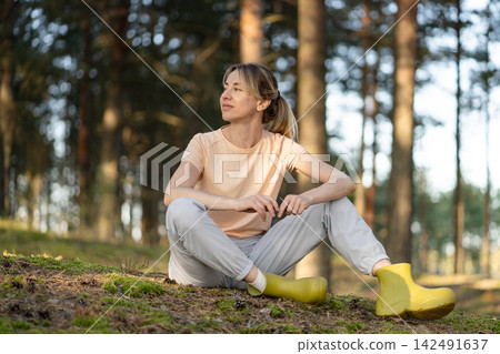 Solitude, inner peace and outdoor activity, positive woman sits on forest ground enjoys quiet moment Solitude, inner peace and outdoor activity, positive woman sits on forest ground enjoys quiet moment 142491637