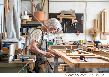 Handwork, skills and craftsmanship in restoration business, focused man restorer repairs wooden door Handwork, skills and craftsmanship in restoration business, focused man restorer repairs wooden door 142491646