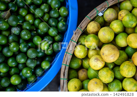 Street food market selling various kinds of citruses, baskets with fresh ripe green and yellow limes Street food market selling various kinds of citruses, baskets with fresh ripe green and yellow limes 142491828