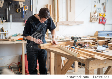 Restoration workshop settings and woodworking, focused man restorer rebuilding frame at worktable. 142491834